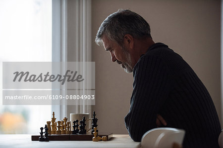 Attentive man playing chess at home