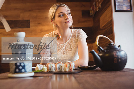 Woman eating sushi in restaurant