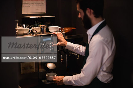 Waiter making cup of coffee from espresso machine