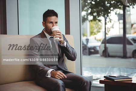 Businessman having coffee while sitting on sofa
