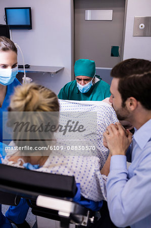 Medical team examining pregnant woman during delivery while man holding her hand