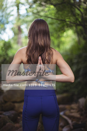 Rear view of woman performing yoga in forest