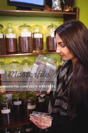 Beautiful woman smelling jar of coffee beans in shop
