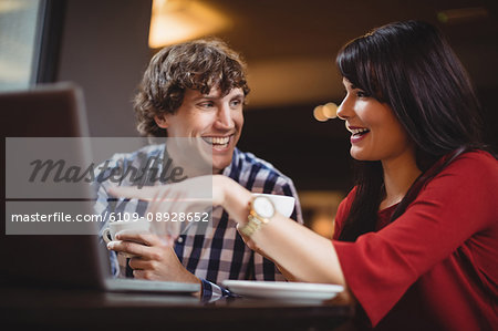 Couple using laptop while having coffee in restaurant