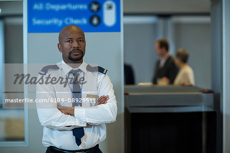 Portrait of airport security officer standing with arms crossed in airport terminal
