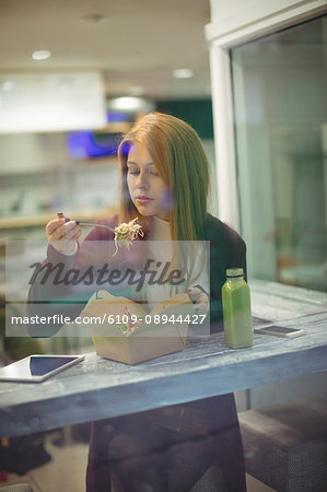 Beautiful woman eating salad in the restaurant