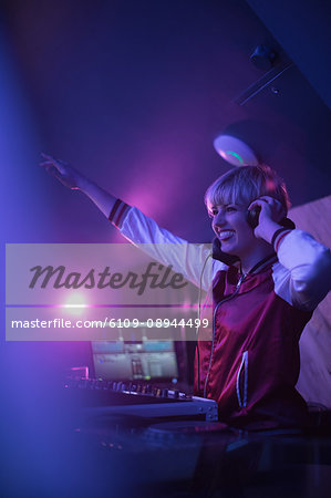 Pretty female dj waving her hand while playing music in bar