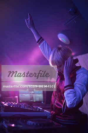 Pretty female dj waving her hand while playing music in bar Pretty female dj waving her hand while playing music in bar