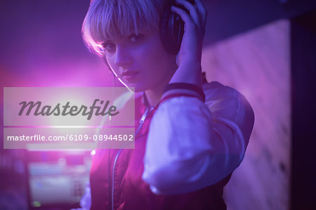 Portrait of female dj listening to music in headphones at bar