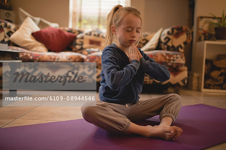 Girl performing yoga in living room at home