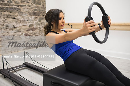 Woman exercising with pilates ring in gym