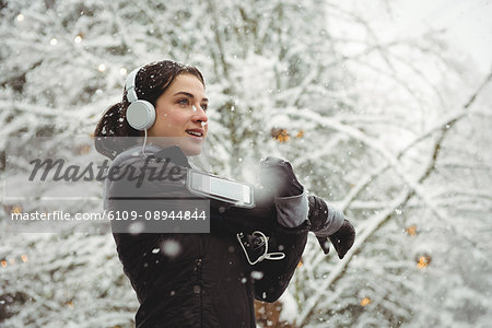 Woman listening to music in headphones from smart phone during winter