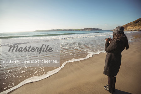 Woman taking photos on digital camera at beach during day