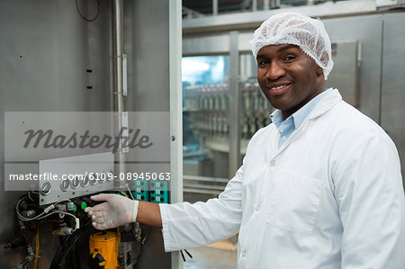 Portrait of confident male worker operating machine in juice factory