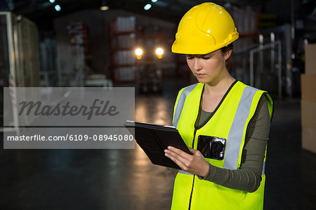 Portrait of beautiful young woman using tablet pc in factory