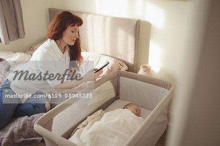 Mother taking picture of baby sleeping in crib at home
