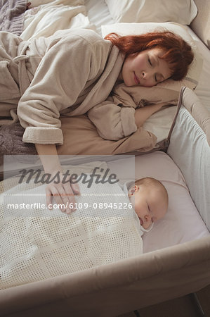 High angle view of mother and baby sleeping in bedroom