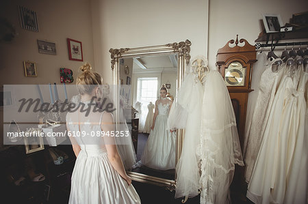 Young bride in a white dress looking into mirror in a boutique