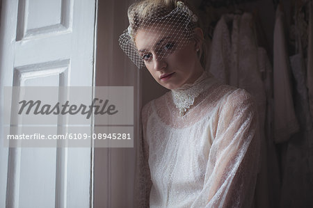 Portrait of young bride standing near window in a boutique