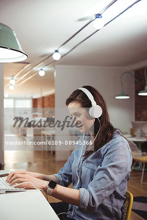 Female executive using laptop at desk in the office