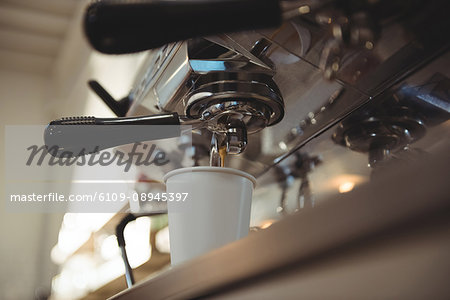 Close-up of machine making cup of coffee in cafe