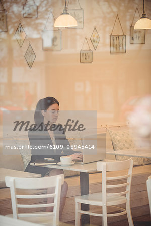 Businesswoman using laptop at table in coffee shop