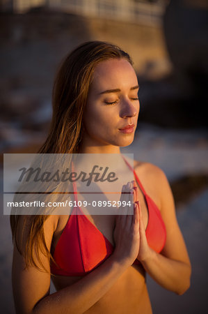 Beautiful woman meditating on beach