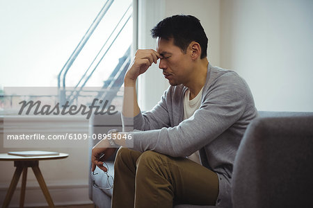 Tensed man sitting on sofa in living room