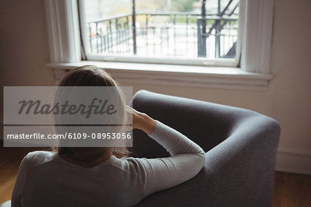 Rear view of woman sitting on sofa in living room