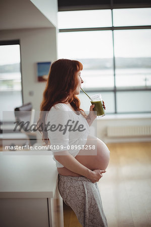 Thoughtful pregnant woman drinking juice