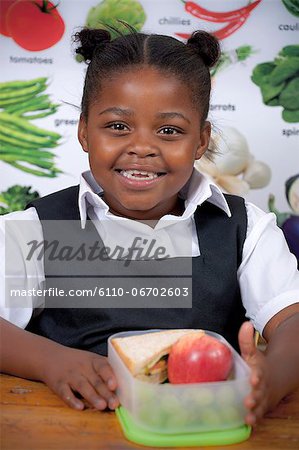 Young African schoolgirl sitting with her lunch smiling at camera