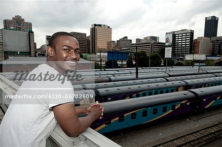Young African male standing with a Johannesburg city scene in the background