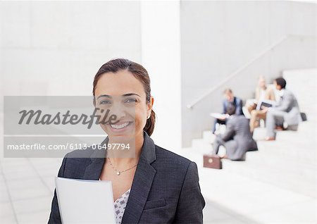 Portrait of confident businesswoman with co-workers in background