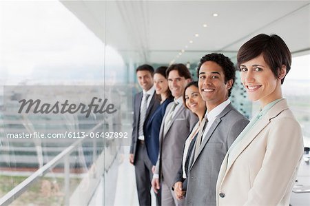 Portrait of smiling business people at window in conference room