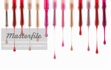 Close up of multicolor fingernail polish dripping from brushes
