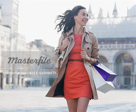 Smiling woman with shopping bags walking in St. Mark's Square in Venice