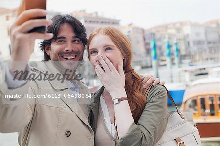 Laughing couple taking self-portrait with camera phone in Venice