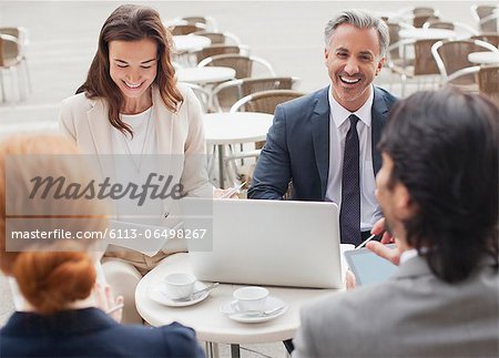 Laughing business people meeting at sidewalk cafe