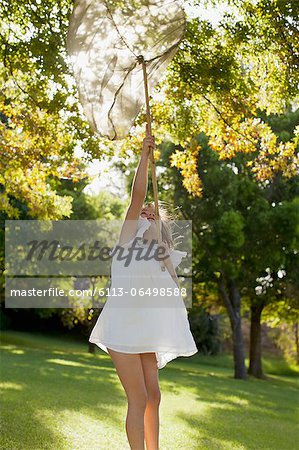 Girl in dress holding butterfly net overhead