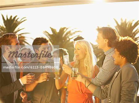 Friends toasting cocktails on sunny balcony