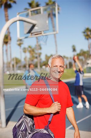 Older man carrying gym bag on court