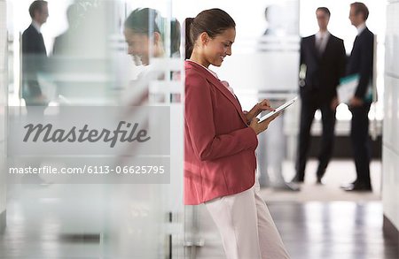 Businesswoman using digital tablet in office hallway