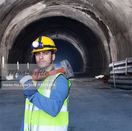 Worker holding sledgehammer in tunnel