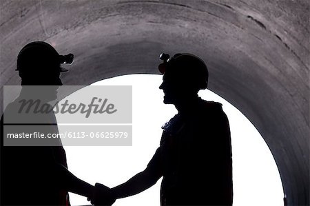 Silhouette of workers shaking hands in tunnel