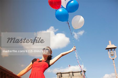 Woman with bunch of balloons on urban bridge