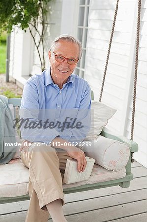 Smiling man sitting on porch swing