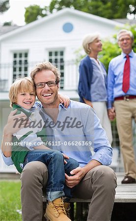 Father and son smiling outside house