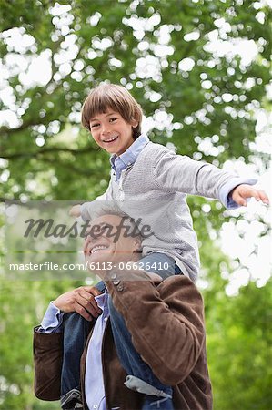 Man carrying grandson on shoulders outdoors