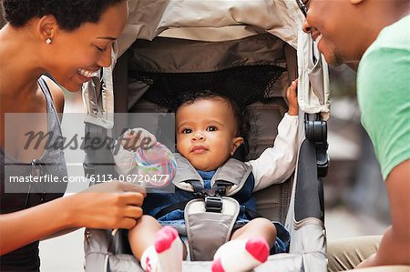 Parents talking to baby in stroller on city street