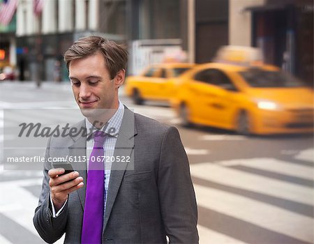 Businessman using cell phone on city street